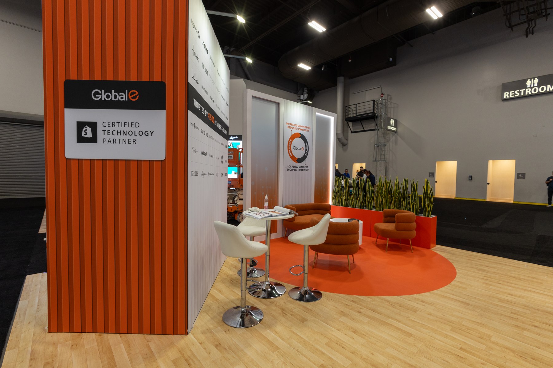 Orange slatted booth wall, screen, and meeting area