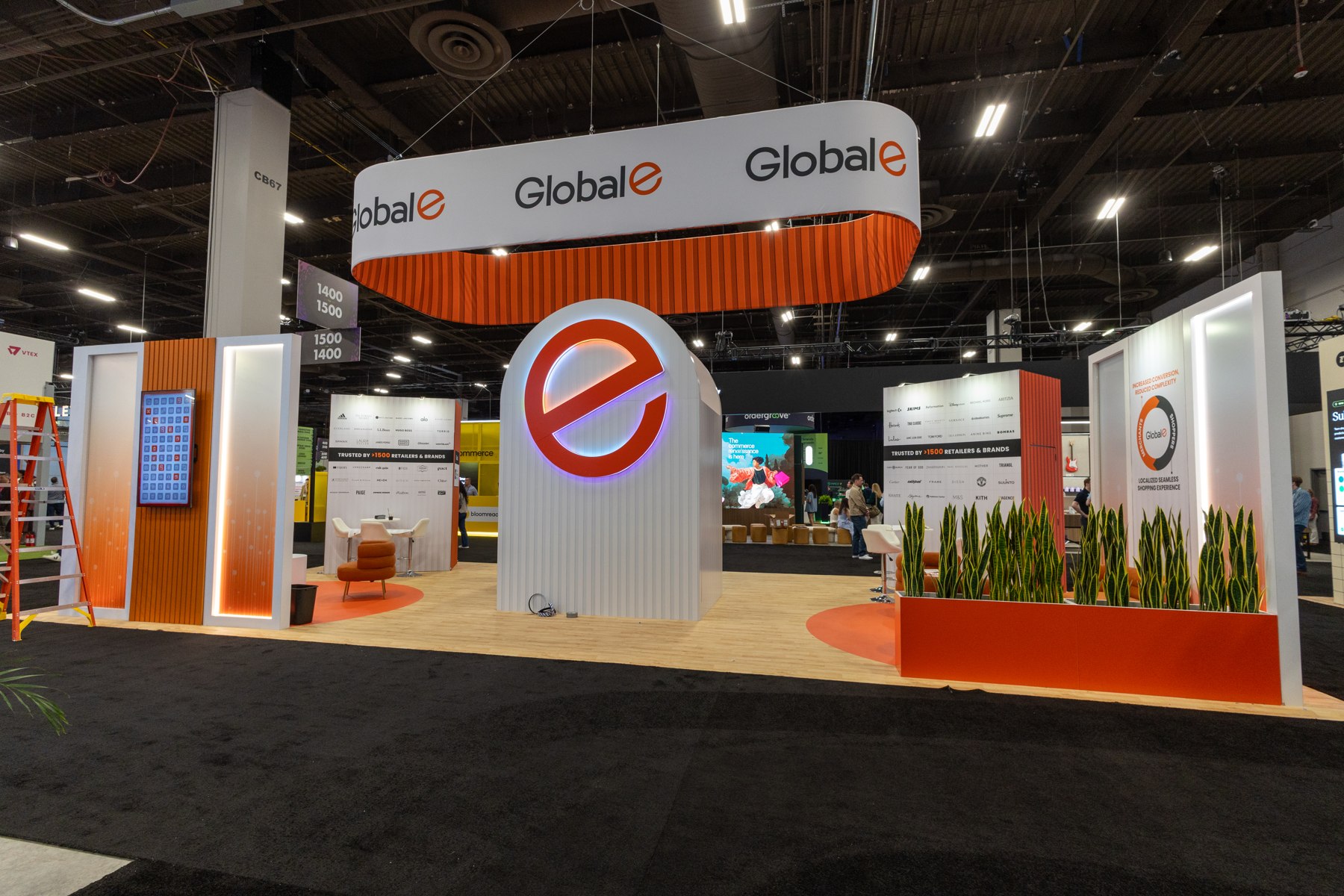 Global-e exhibition stand with overhead signage and meeting tables